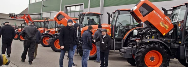 mężczyźni stojący przy nowoczesnych traktorach